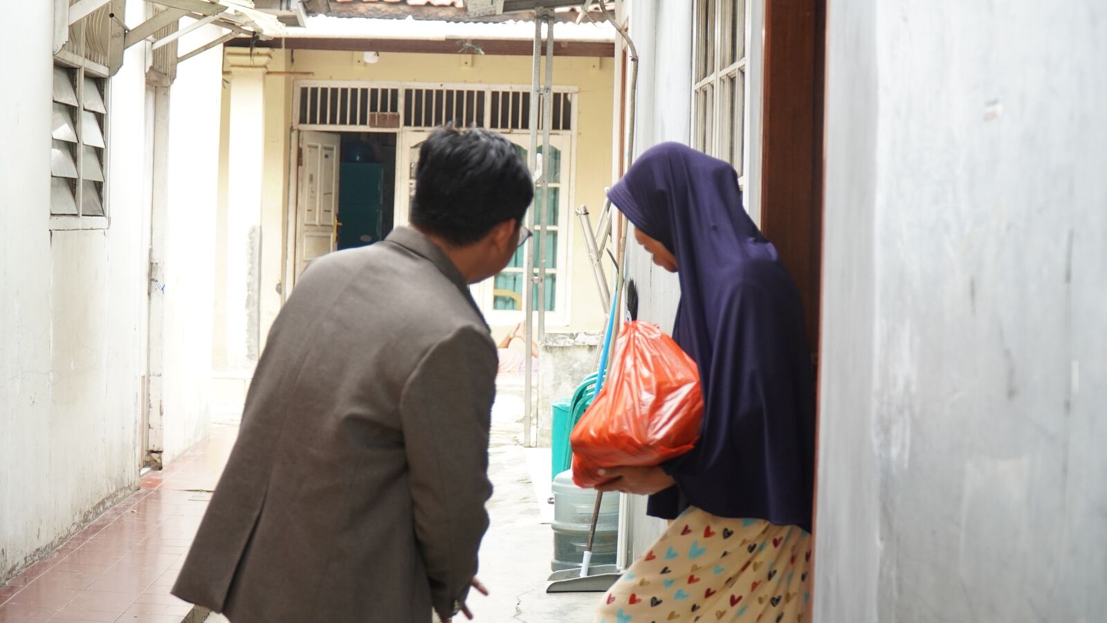 Petugas PSQ menyerahkan paket sembako kepada warga di depan rumahnya